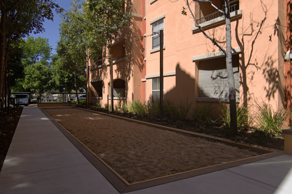 A sidewalk runs along a building with a red brick facade.