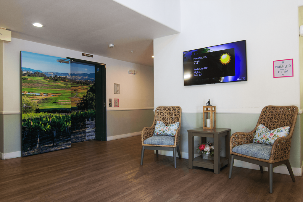 A room with a television on the wall and two chairs in front of it.
