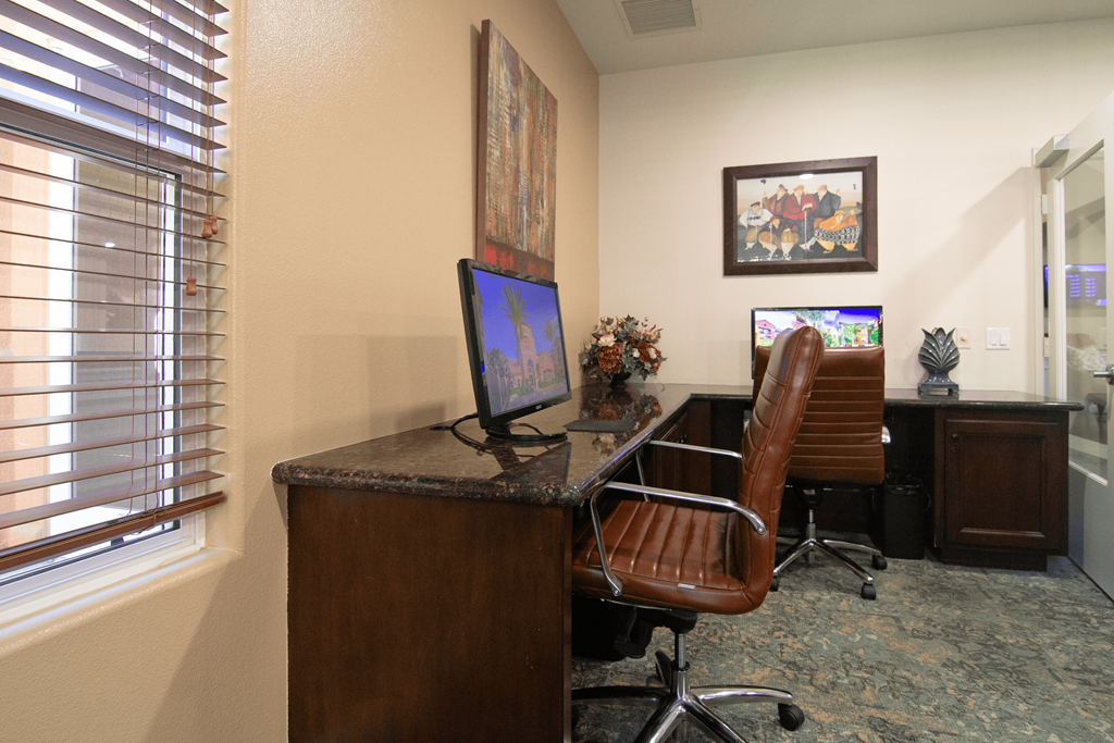 A brown leather chair is in front of a desk with a computer on it.