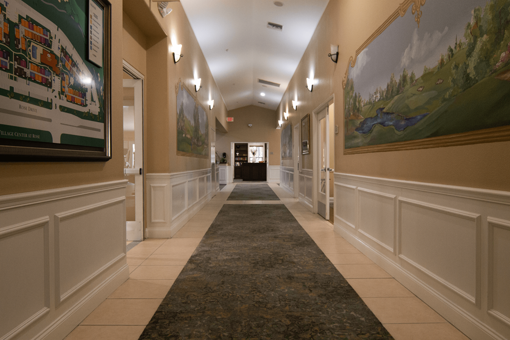 A hallway with a rug and a painting on the wall.
