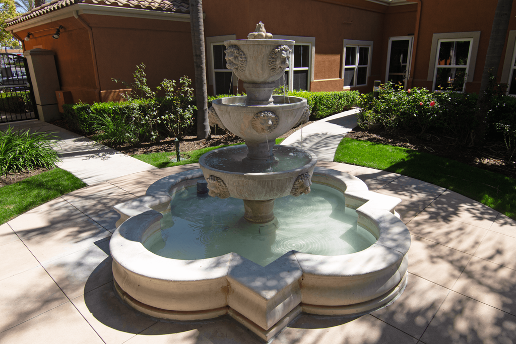 A stone fountain with three tiers of water jets out of a basin.