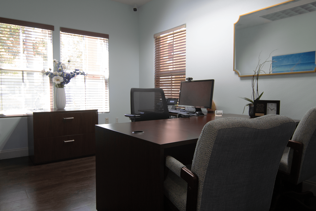 A room with a desk, chairs, and a laptop.