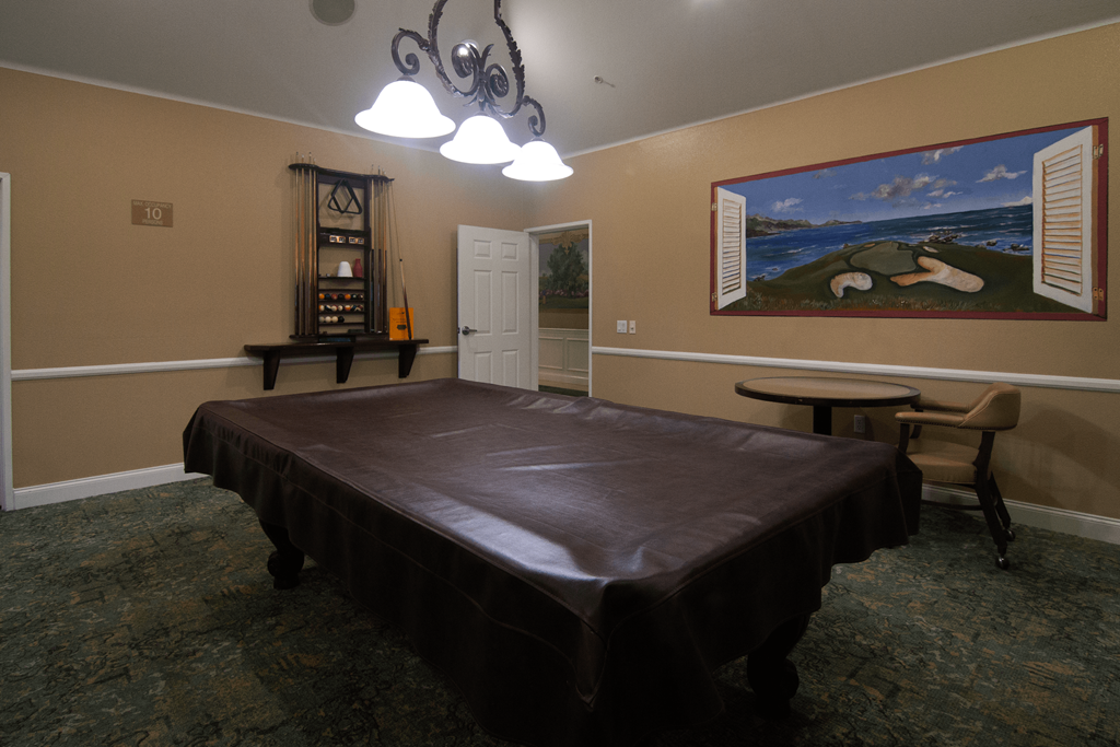 A room with a bed, a chair, and a painting on the wall.