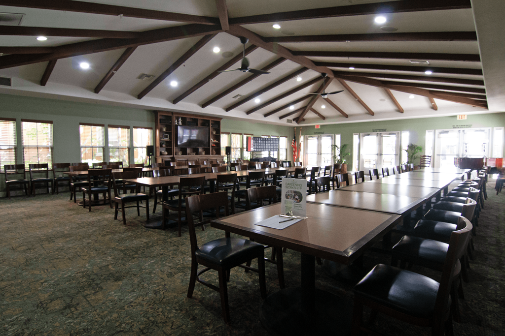 A large room with tables and chairs and a screen tv.