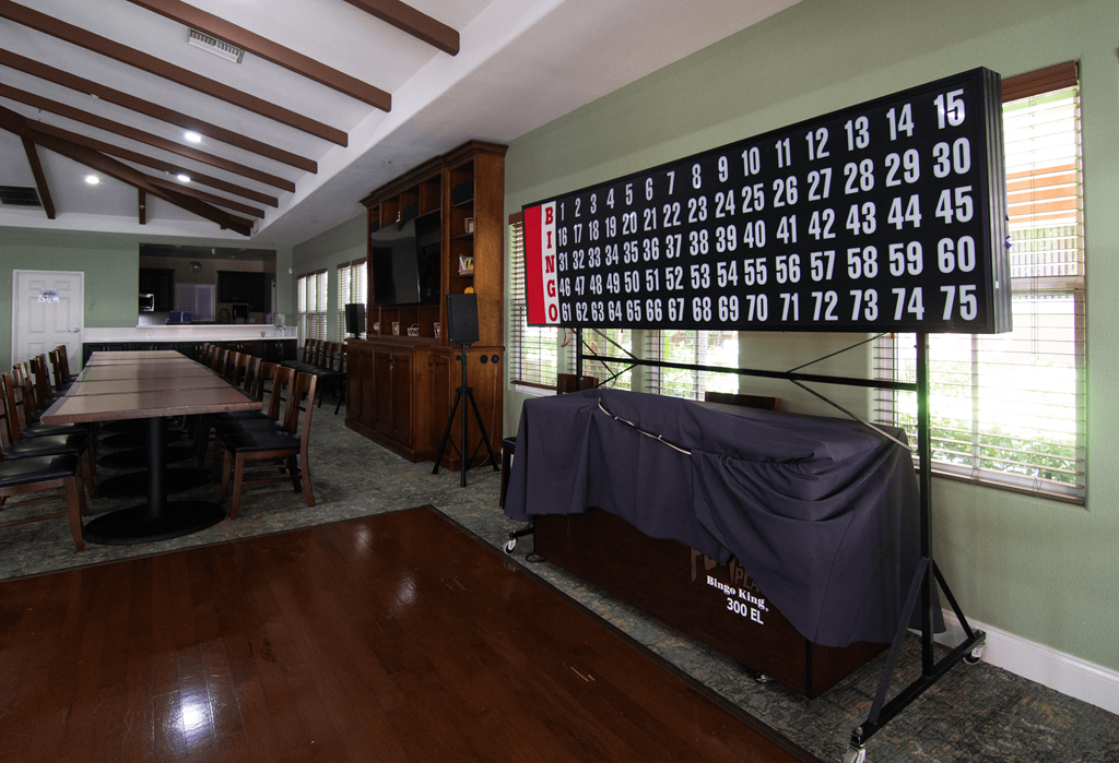 A large room with a long table and chairs, a projector screen, and a wall with numbers from 1 to 75.