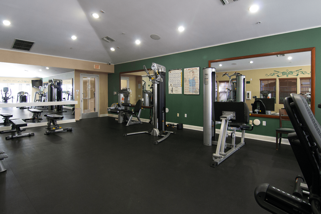 A gym with a variety of equipment including weights and cardio machines.