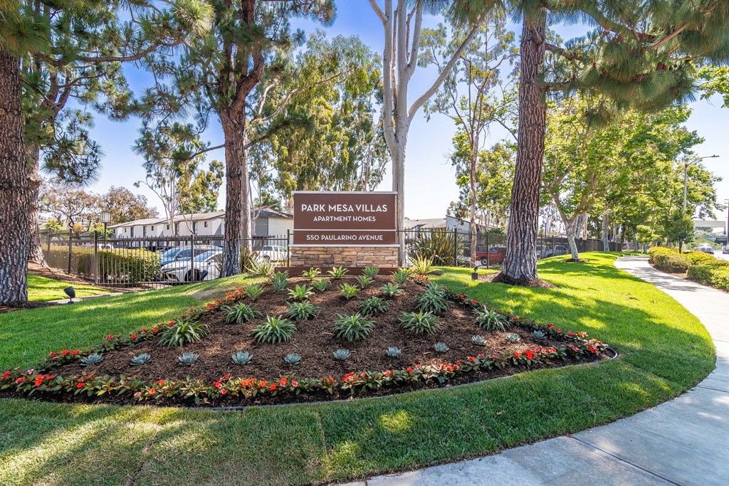a park with a sign and flowers and trees