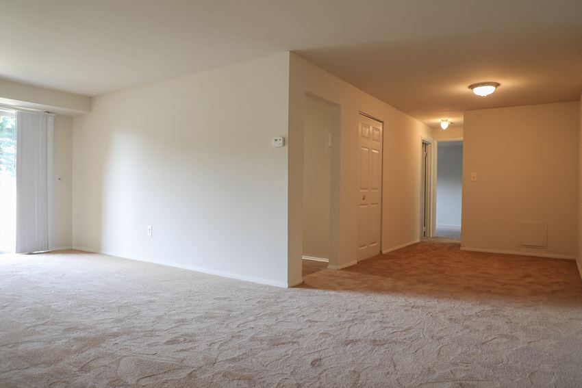 an empty living room with white walls and a door to a hallway