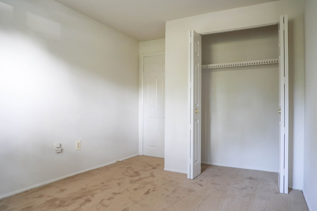 an empty room with white walls and a door to a closet