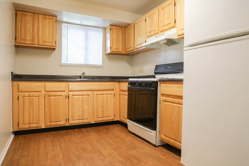 an empty kitchen with wooden cabinets and a stove and refrigerator