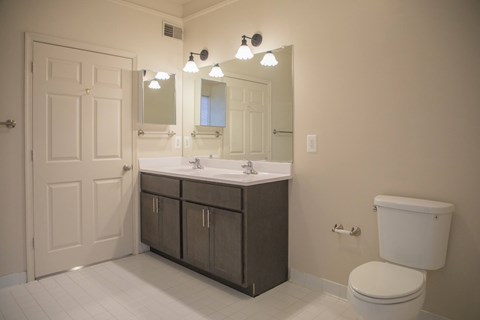 A bathroom with a toilet, sink, and mirror.