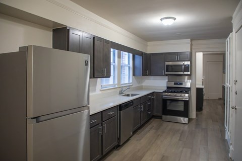 A kitchen with a refrigerator, oven, and sink.