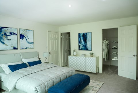 A bedroom with a large bed and a dresser with a mirror at Cascades Overlook Apts., Owings Mills