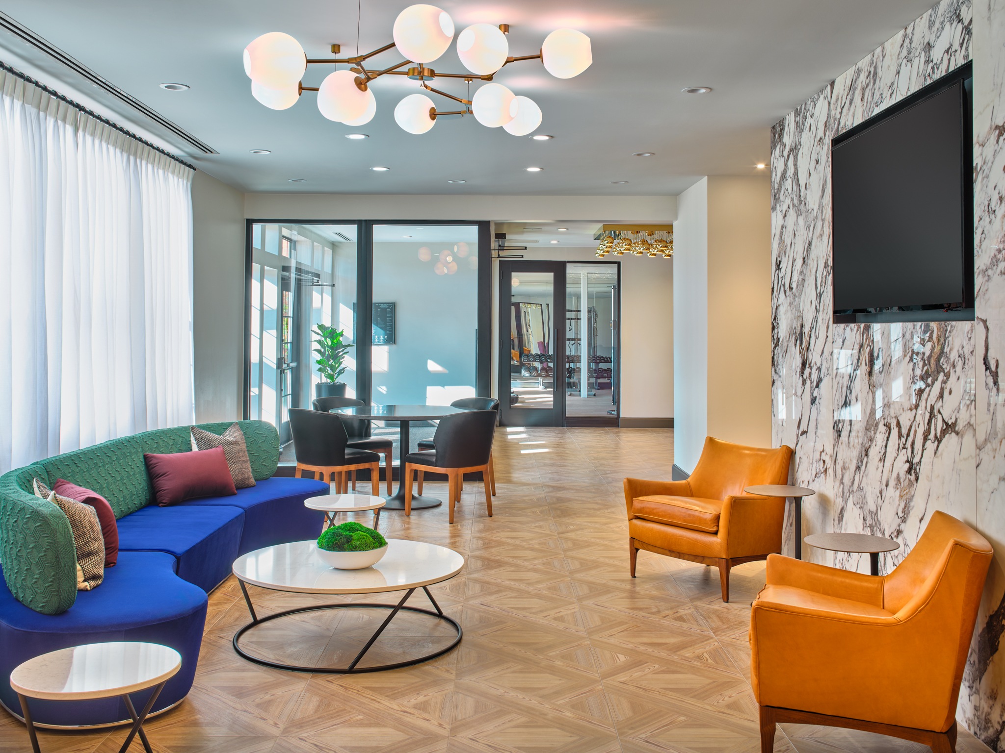 A living room with a blue couch, a coffee table, and a television mounted on the wall.