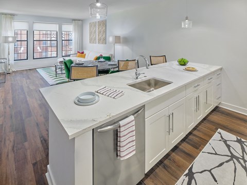 A kitchen with a white countertop and wooden floors.