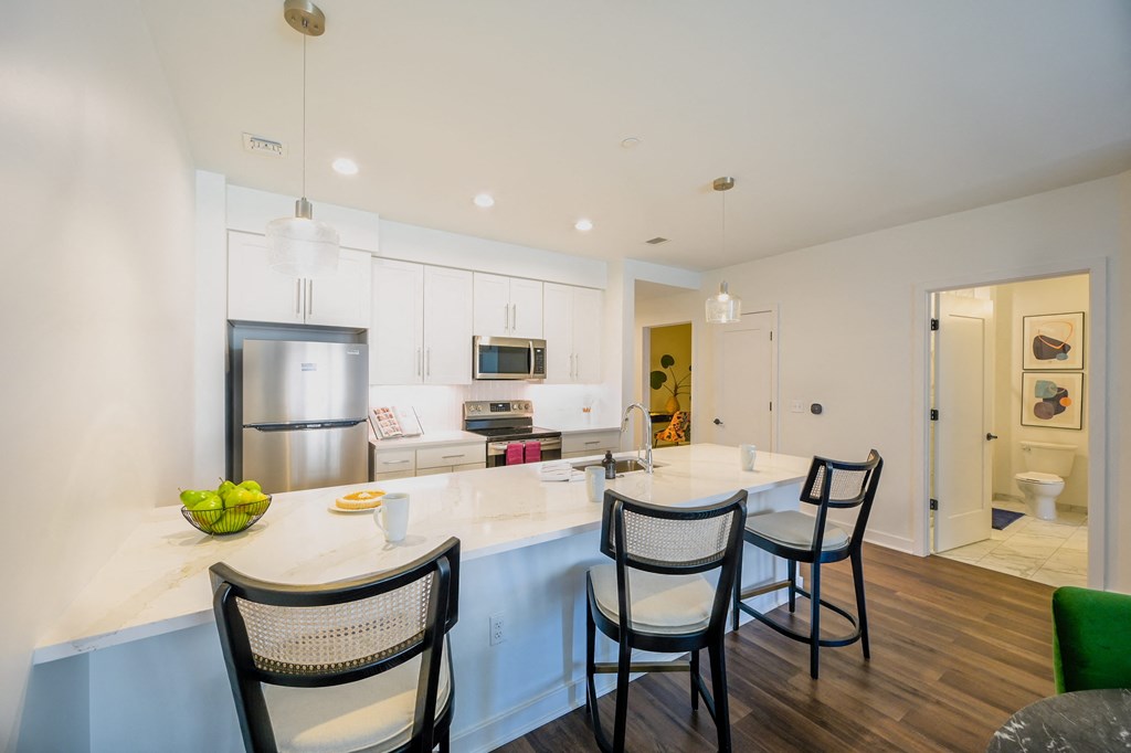 a kitchen with white cabinets and a large island with chairs at Ingram Manor, Pikesville, MD