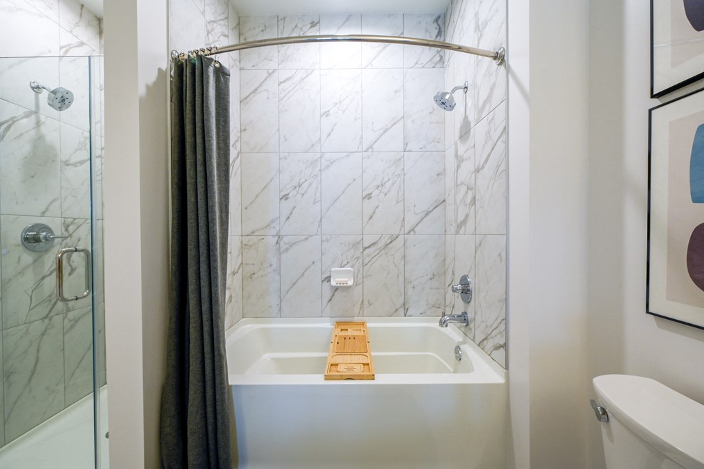 a bathroom with a shower and a bath tub with a wooden tray in it at Ingram Manor, Pikesville, MD