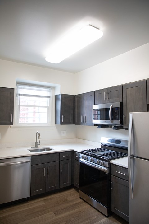 A kitchen with a stove, sink, and refrigerator.