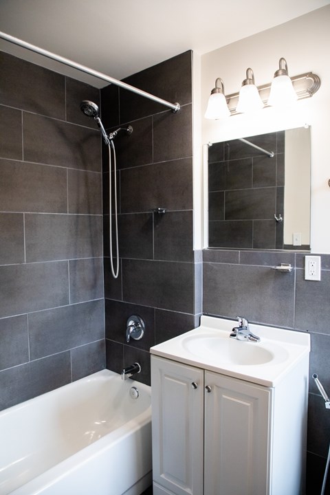 A white bathroom sink with a white tub and a white cabinet.