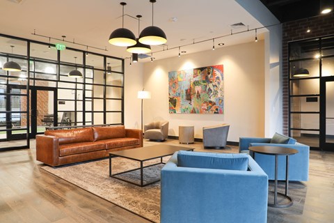 A modern living room with a large painting on the wall and a brown leather couch.