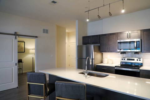 A kitchen with a white counter top and a stainless steel refrigerator.