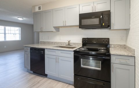 A kitchen with black appliances and white cabinets.