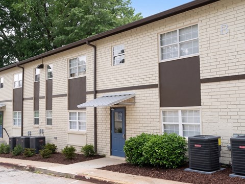 A building with a blue door and windows with air conditioning units in front.