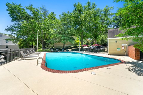 A small pool surrounded by trees and a fence.