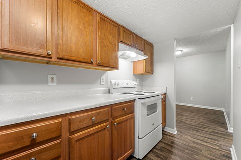 A kitchen with wooden cabinets and a white stove top oven.at Bradford Gwinnett Apartments and Townhomes, Norcross, GA 30071
