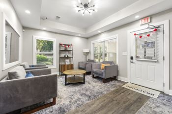 A living room with a grey couch, a wooden coffee table, and a white door.at Bradford Gwinnett Apartments and Townhomes, Norcross, 30071