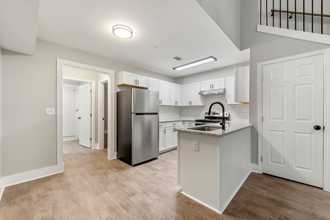 Renovated and open kitchen with white cabinets and stainless steel appliances at Crogman School Lofts, Atlanta, 30315