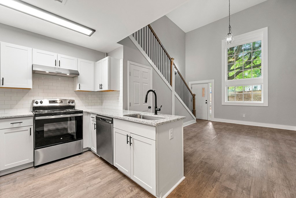 Renovated and open kitchen with white cabinets and stainless steel appliances at Crogman School Lofts, Atlanta, 30315