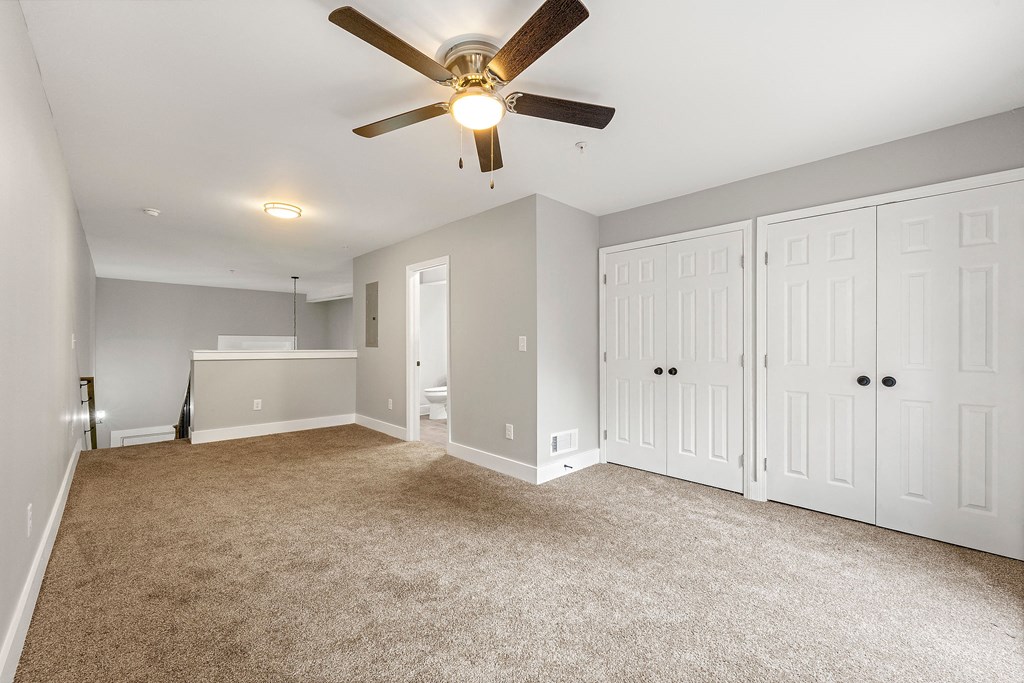 Master bedroom with a ceiling fan and white closet at Crogman School Lofts, Atlanta, 30315