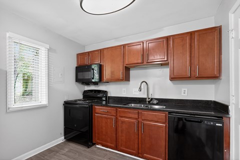 A kitchen with black appliances and brown cabinets.