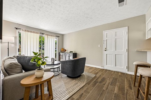 A living room with a grey couch, a wooden table, and a white door.