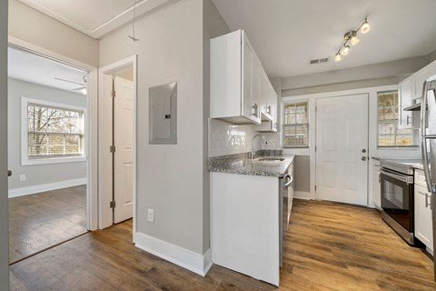 A kitchen with white cabinets and a wooden floor.