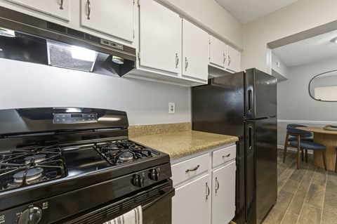 A black stove and refrigerator in a kitchen with white cabinets.