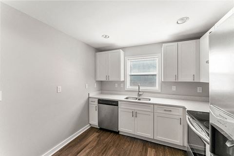 a small kitchen with white cabinets and a stainless steel dishwasher