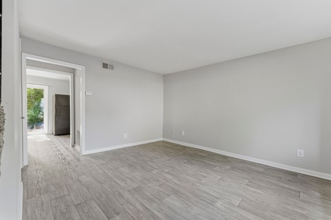 A room with a doorway leading to a balcony and a grey floor.