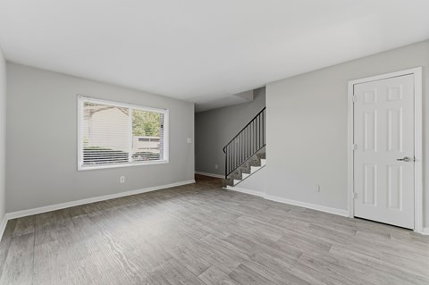A room with a staircase and a window with blinds.