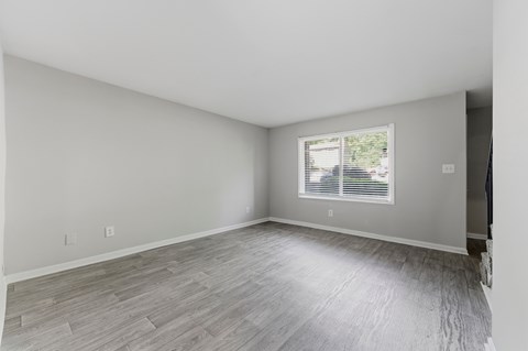 A room with a window and wooden flooring.