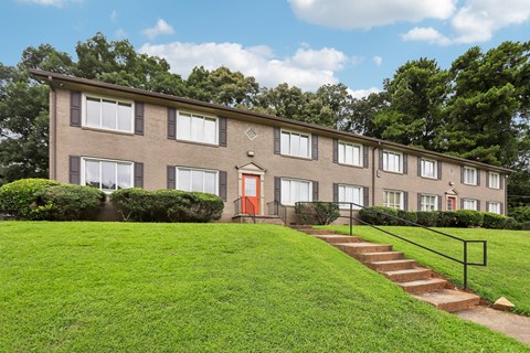 A building with a red door is surrounded by a green lawn.