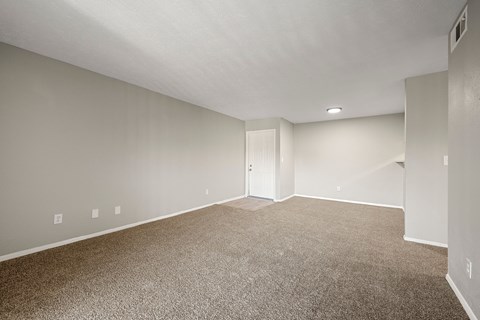 A spacious room with carpeted floor and white walls.