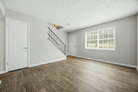 A room with a wooden floor and a staircase with a metal railing.