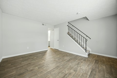 A room with wooden flooring and a staircase with metal railings.