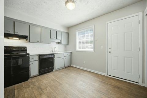 A kitchen with black appliances and white cabinets.