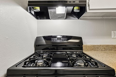 A black gas stove with four burners is installed in a kitchen.