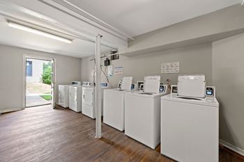 a row of washers and dryers in a room with a wood floor at Georgian Oaks Apartments Apartments, Smyrna , Georgia
