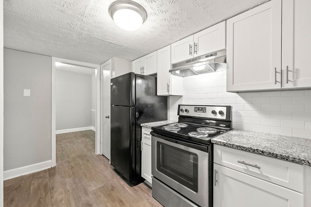Renovated kitchen with white cabinets and black appliances at Pines at Lawrenceville Decatur 30033
