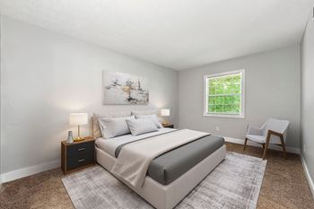 a bedroom with a bed and a chair and a window at Pines at Lawrenceville Apartments in Decatur, Georgia 30033